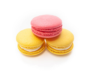 Fototapeta na wymiar three pyramid shaped macaroons one pink and two yellow on a white isolated background