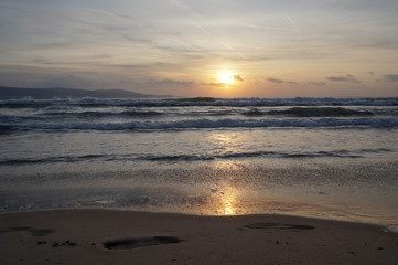 Golden dawn at sea, waves running onto the sand