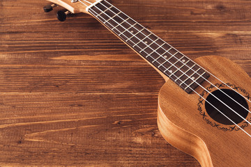 Fototapeta premium brown ukulele with white strings on wooden background