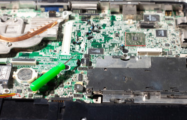 repairing a broken laptop, unscrewing screws with small screwdrivers