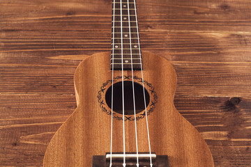 Obraz premium beatiful soprano ukulele with white strings made of zebrawood on aged wood background