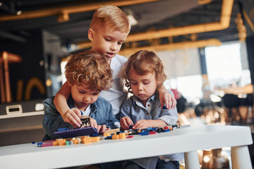 Little friends have fun with construction toys in playroom. Kindergarten educational games