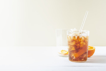 Cold brew coffee mocktail with orange peel and glass straw.Glass with citrus esprecco tonic with ice on white background.Refreshing summer non-alcoholic drink concept.Horizontal orientation,copy space
