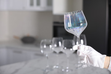 Person in white glove checking cleanliness of glass indoors, closeup. Space for text