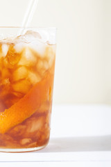 Cold brew coffee mocktail with orange peel close-up.Glass with citrus esprecco tonic with ice on white background.Refreshing summer non-alcoholic drink concept.Vertical orientation,copy space
