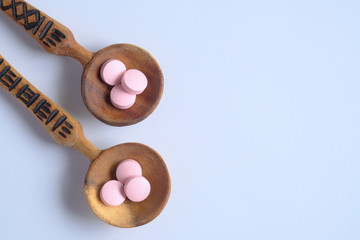 top view of pills on wooden spoon on white background 