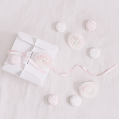 Gift or present box with pink ribbon and flowers on white background top view. Birthday or holiday background. pastel colors