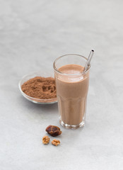 Smoothies of dried fruits, nuts, and chocolate in a glass on a light background