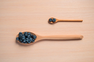 Fresh blueberries lie in a wooden spoon on a natural wooden background. Eco products for human health. Healthy eating concept flat lay. Copy spase