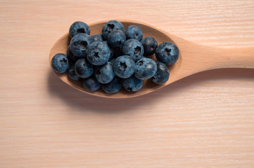 Fresh blueberries lie in a wooden spoon on a natural wooden background. Eco products for human health. Healthy eating concept flat lay. Copy spase