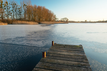 Obraz na płótnie Canvas Wooden jetty and frozen lake, sunny day