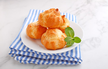 Profiteroles with custard decorated with mint on a marble background