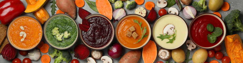 Vegetable soups and ingredients on grey background, top view