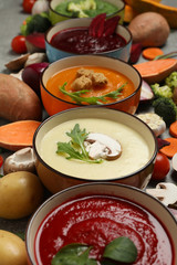 Vegetable soups and ingredients on grey table. Healthy eating