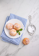 Profiteroles with custard decorated with mint on a marble background, top view