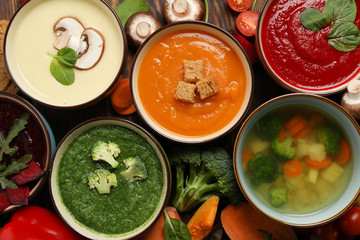 Vegetable soups and ingredients on wooden background, top view