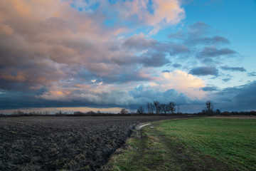 Colorful clouds over fields, road and rural view