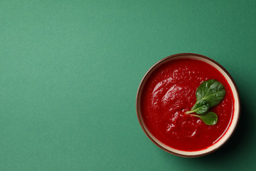 Tomato cream soup on green background, top view