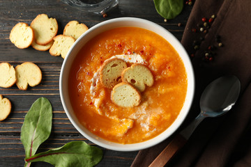 Pumpkin cream soup with croutons on wooden background, top view