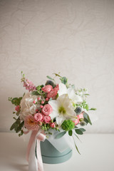 A large flower arrangement in a hat box was created by a florist for a wedding gift. Hydrangea, amarallis, roses and eucalyptus in a bouquet