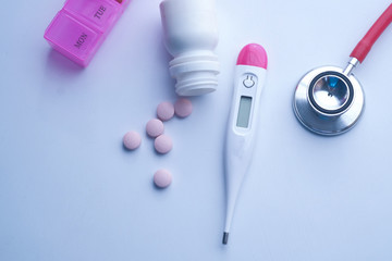 close up of stethoscope, pills and thermometer on pink background 