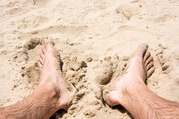 wet male feet in the sand at the beach