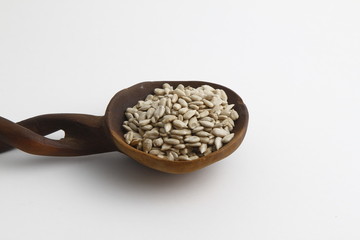 Full spoon of sunflower seed on a wooden board. Wooden spoon on a white background.