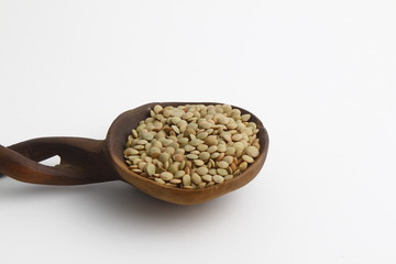 Pile lentil in wooden spoon isolated on white background. Top view.