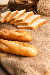 French baguette with slices of bread on tablecloth