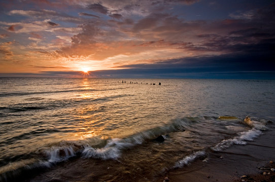 Summer sunrise over Lake Michigan with waves washing up on the shoreline.