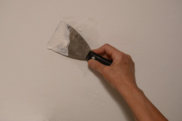 Woman plasterer repairing the wall with putty. Close-up, copy space.