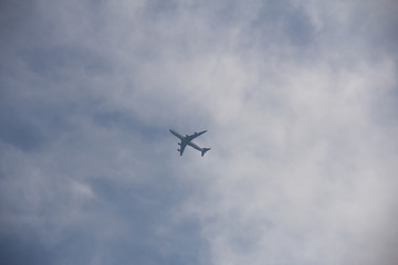Fototapeta na wymiar A single airplane has just taken off from Copenhagen airport and is seen from below as it enters the clouds in a bright summer day