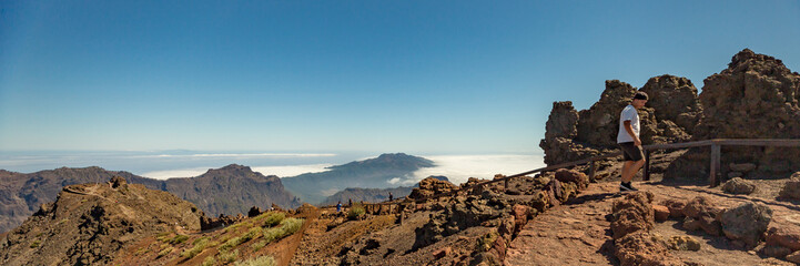 Aerial view of the National Park Caldera de Taburiente, volcanic crater seen from mountain peak of Roque de los Muchachos Viewpoint. El Hierro on horizon line above the clouds. La Palma, Spain