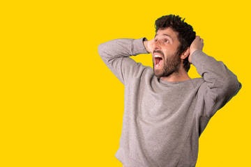 Young handsome man wearing casual sweater standing over isolated yellow background angry and mad screaming frustrated and furious, shouting with anger. Rage and aggressive concept.