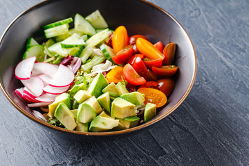 Vegan buddha bowl. Healthy vegetarian salad with cherry tomatoes, cucumber, radish, avocado, lettuce