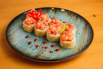 Fresh maki with fish on top, served on a blue plate