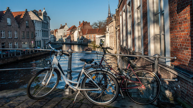 Bicicletas aparcadas en uno de los puentes que unen los canales de Brujas con sus casas t&iacute;picas al fondo