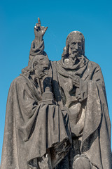 Fototapeta na wymiar Ancient statue of two monks with Bible at the Charles Bridge in Prague at blue sky, Czech Republic, summer, closeup