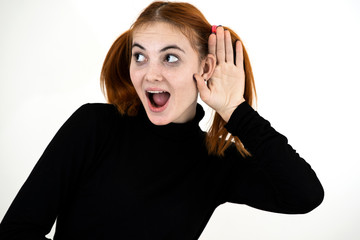 Close up portrait of pretty redhead teenage girl holding a hand to her ear listening to a secret.