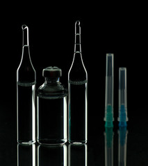 Glass ampoules close up. Medical ampoules. Medical ampoules, syringe needles on a black background.