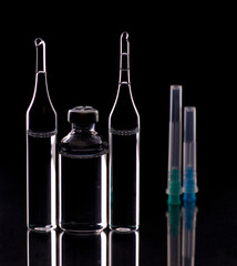 Glass ampoules close up. Medical ampoules. Medical ampoules, syringe needles on a black background.