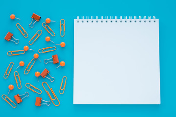 Empty spiral notebook and clips on blue background. Copy space. Education, planning concept. Copy space.