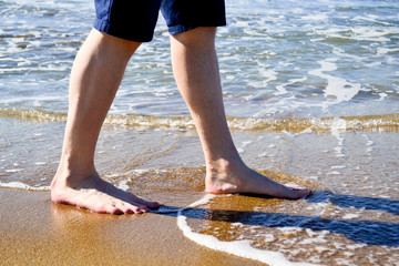 A man walks on a Sunny beach in the water. Copy space for background