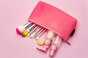 Makeup cosmetic set in bag on pink background