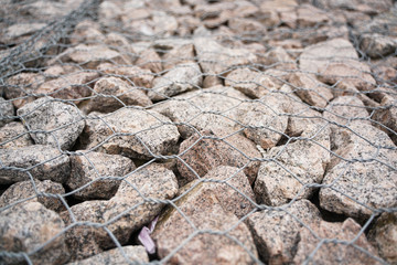 Detail shot of a stone retaining wall with stones in a steel cage