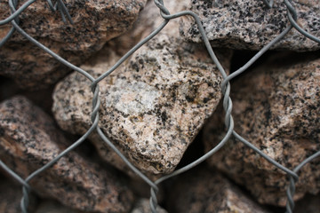 Detail shot of a stone retaining wall with stones in a steel cage