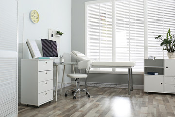 Modern medical office interior with computer and examination table - Powered by Adobe