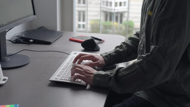 Mann tippt auf Tastatur im Home Office