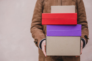 Person in brown coat holding colorful paper carboard package