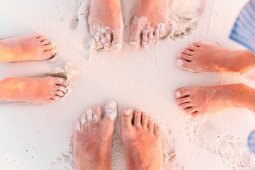Close-up of the feet of family on the white sandy beach